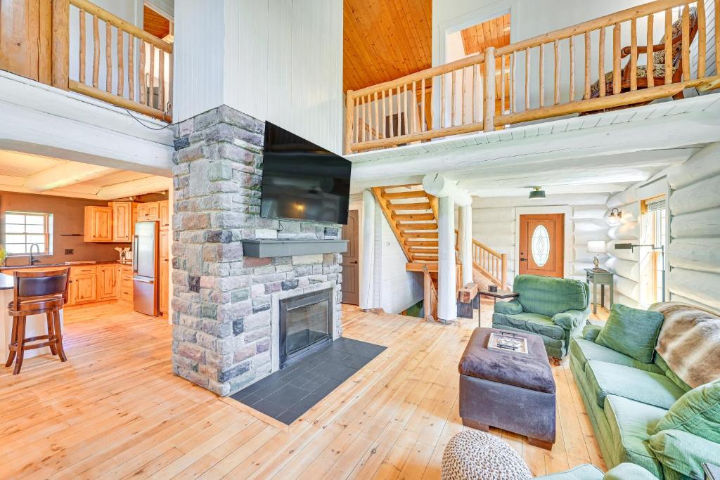 a living room with a stone fireplace and a staircase at 4 Mi to Dtwn Spacious Family Cabin in Jonesville! in Jonesville