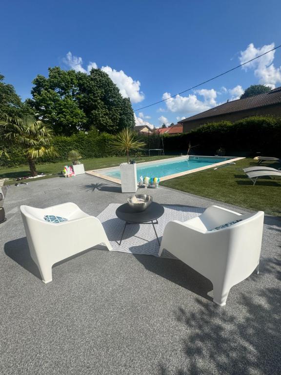 two white chairs and a table next to a pool at Cozy apartment in Neuville-les-Dames