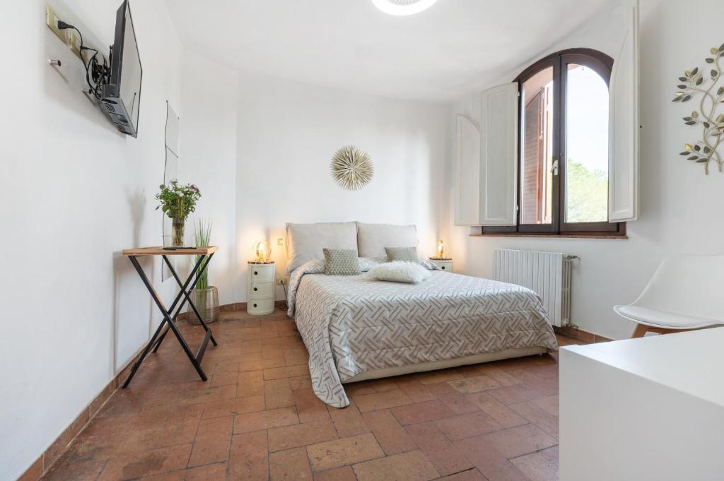 a white bedroom with a bed and a window at Antico Podere Il Bugnolo in Poggibonsi