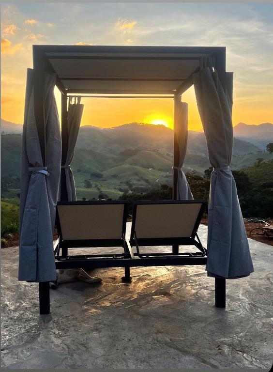 a bed with the sunset in the background at Cabana do Mato com ofurô, cesta para café da manhã e pet friendly in Gonçalves