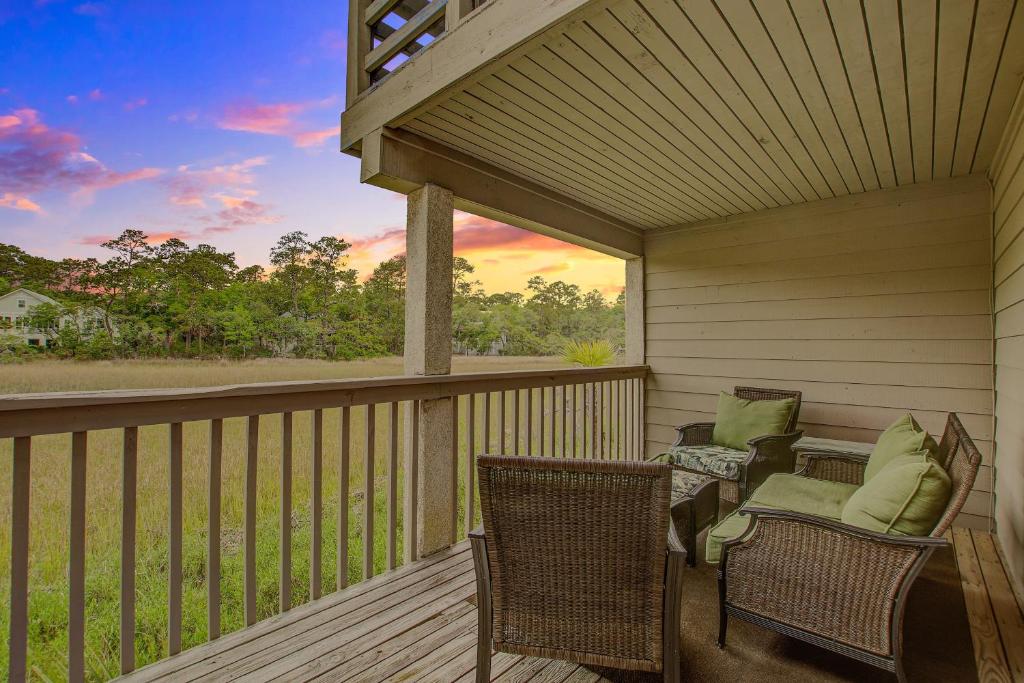 a porch with two chairs and a table with a sunset at Creekwatch 1245 in Seabrook Island