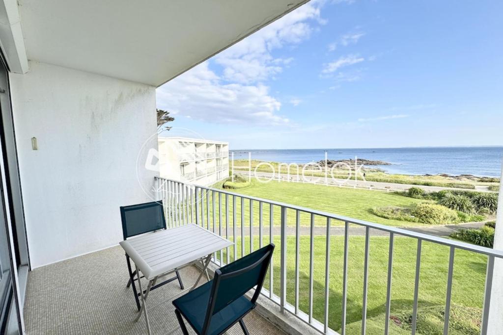 un balcon avec une table et des chaises et l'océan dans l'établissement Évasion Marine - Vue mer imprenable 180, à Quiberon