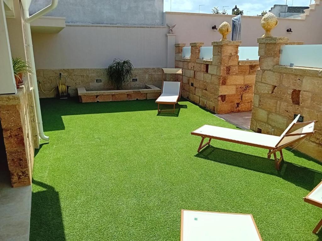 a patio with green grass and a couch and chairs at Casa vacanze da Pino A in Torchiarolo