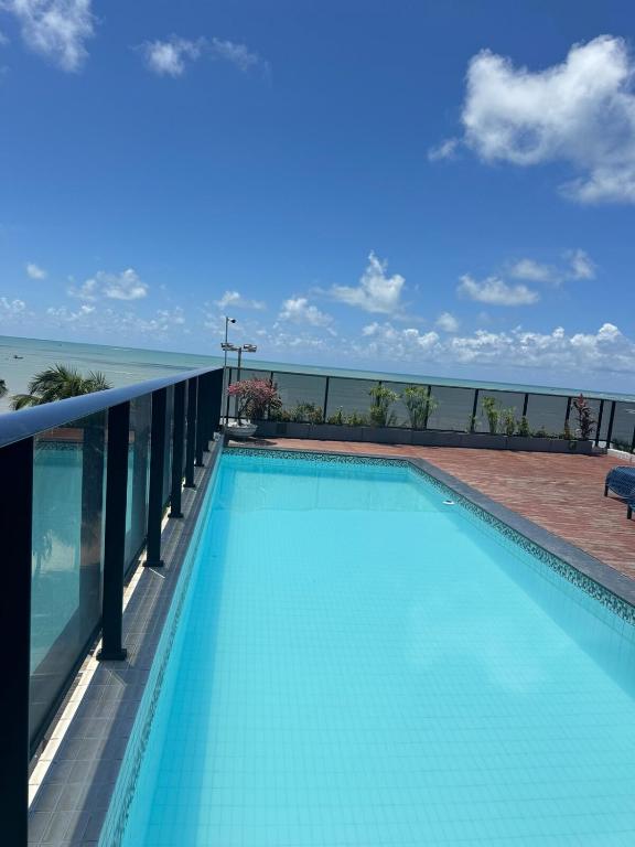 a swimming pool with the ocean in the background at Suites Premium 2 quartos in João Pessoa