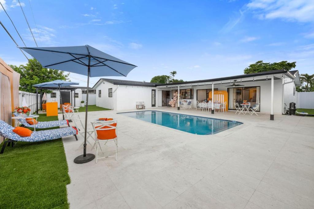 a house with a swimming pool and an umbrella at Sheraton Villa 3BR with Pool 10 Mins from Hard Rock Stadium in Miramar