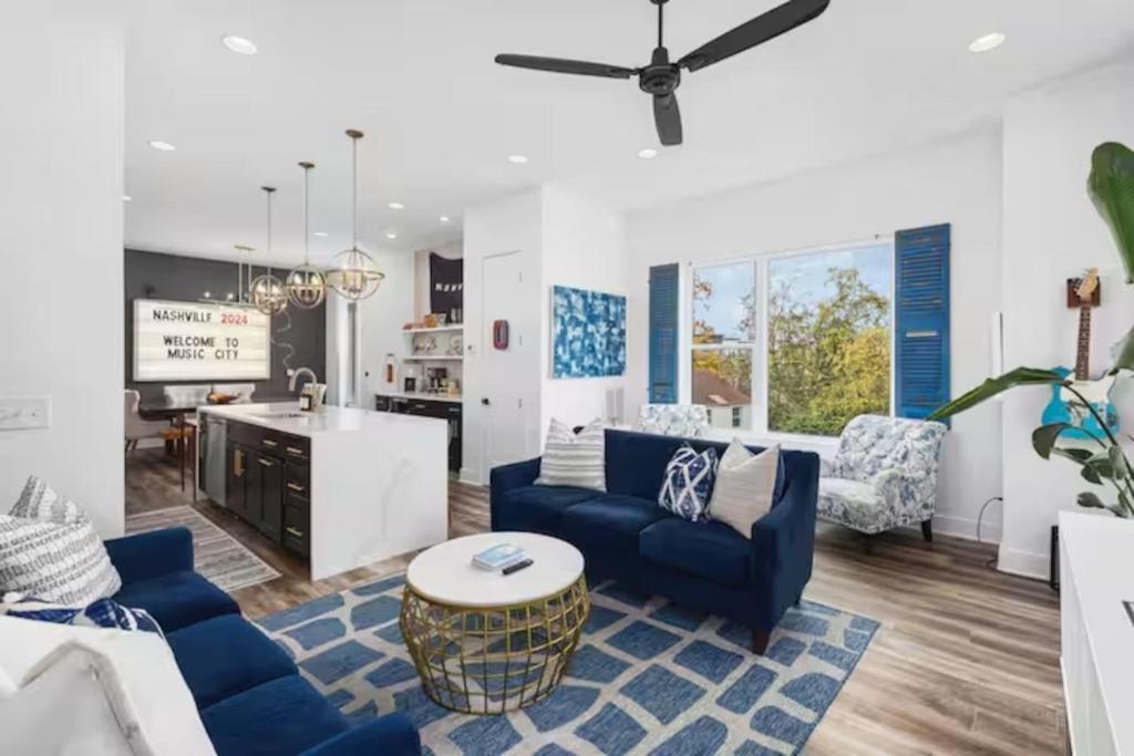 a living room with blue couches and a kitchen at Walk Geodis Stadium Restaurants Rooftop EV Garage in Nashville