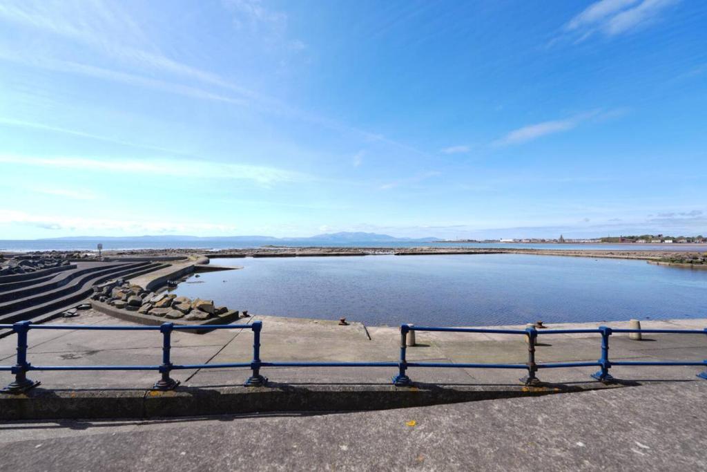 a bench sitting next to a body of water at Caledonia by the Sea in Saltcoats