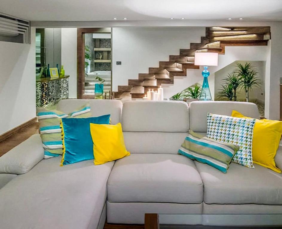 a living room with a white couch with colorful pillows at Reno Villa 4Br in Sheikh Zayed