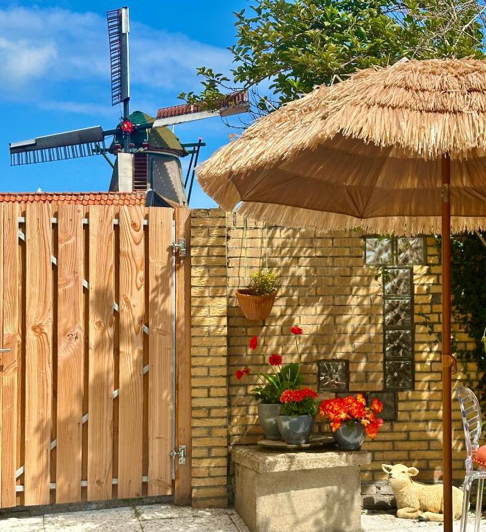 a wooden fence with an umbrella and flowers in pots at Havenhuis TEXEL, per week or weeks Saturday-Saturday in Oudeschild