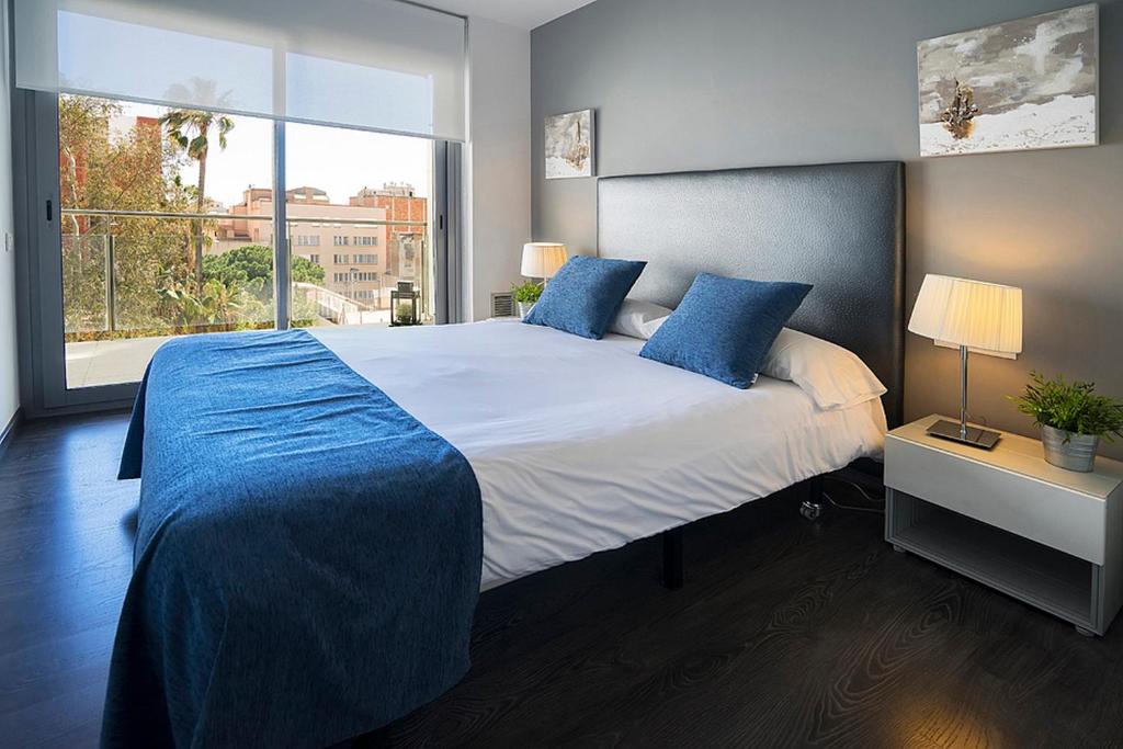 Un dormitorio con una cama con almohadas azules y una ventana en AB Gracia Parc Guell, en Barcelona