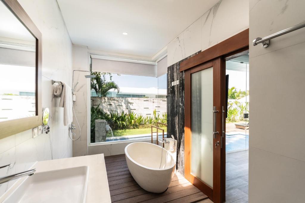 スミニャックにあるThe Daha Luxury Villasのバスルーム(バスタブ付)、大きな窓が備わります。