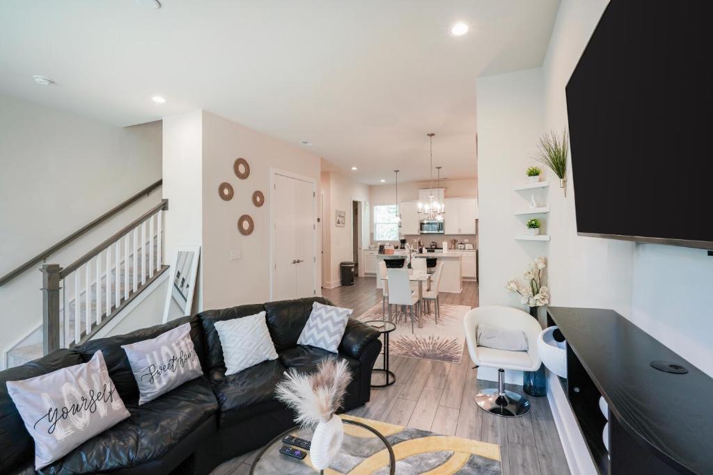 Hotel Stylish 3BR Home in CLT, Close to Downtown, Airport, WFH & Parking & Family Friendly & Business Ready, a living room with a black couch and a dining room at Stylish 3BR Home in CLT, Close to Downtown, Airport, WFH & Parking & Family Friendly & Business Ready in Charlotte