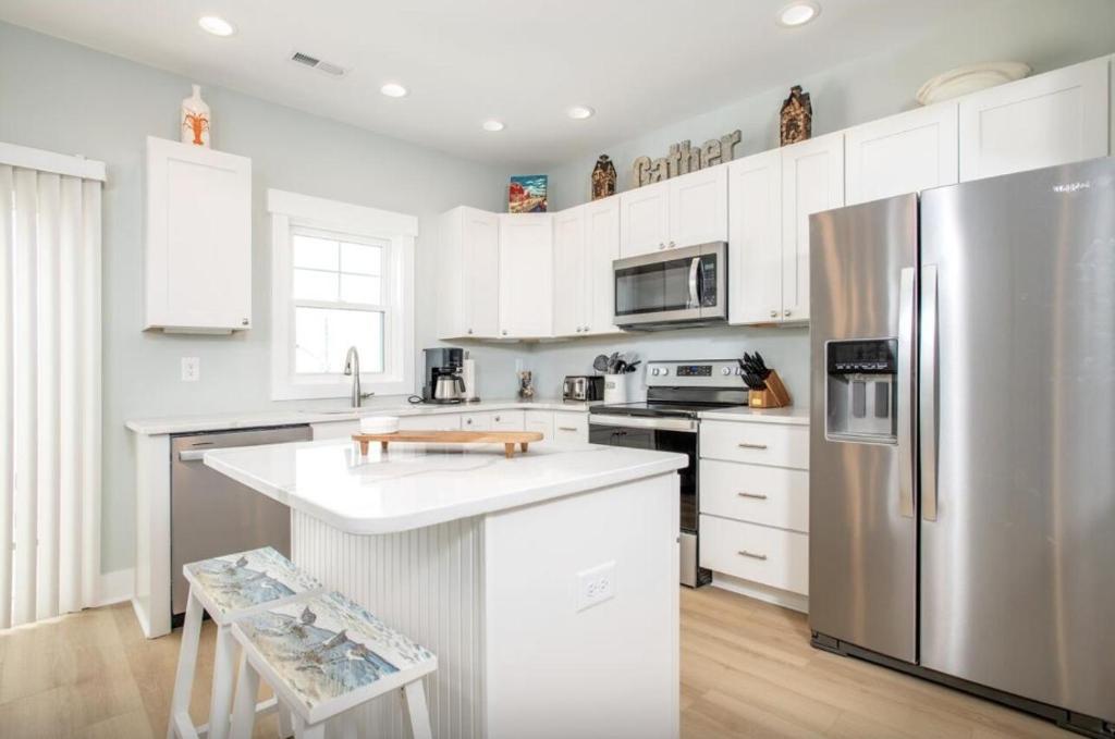 a kitchen with white cabinets and a stainless steel refrigerator at Marley's Retreat townhouse in Atlantic Beach