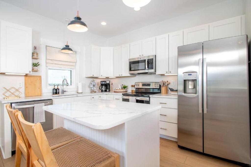 a kitchen with a stainless steel refrigerator and white cabinets at SALTY DALTY & THREE BUOYS townhouse in Atlantic Beach