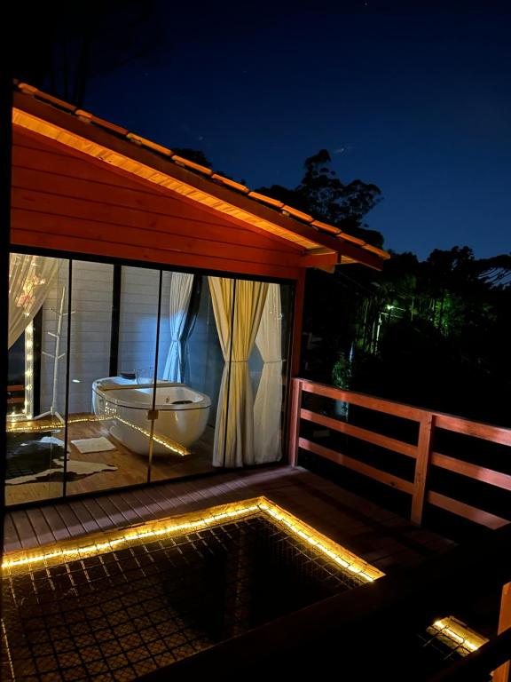 a bath tub sitting on a deck with a house at Cabana Recanto Dona Ilza in Biguaçu