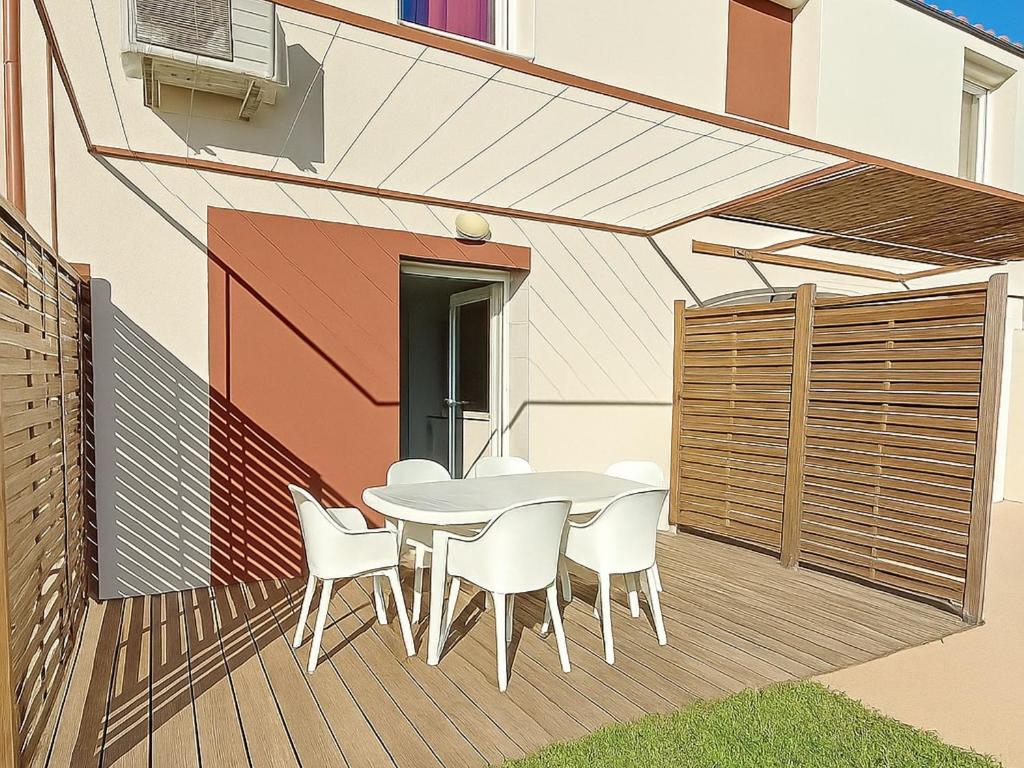 une table et des chaises blanches sur une terrasse en bois dans l'établissement Pavillon climatisé, proche plages et village, terrasse, parking, animaux admis - Argelès-sur-Mer - FR-1-732-4, à Argelès-sur-Mer