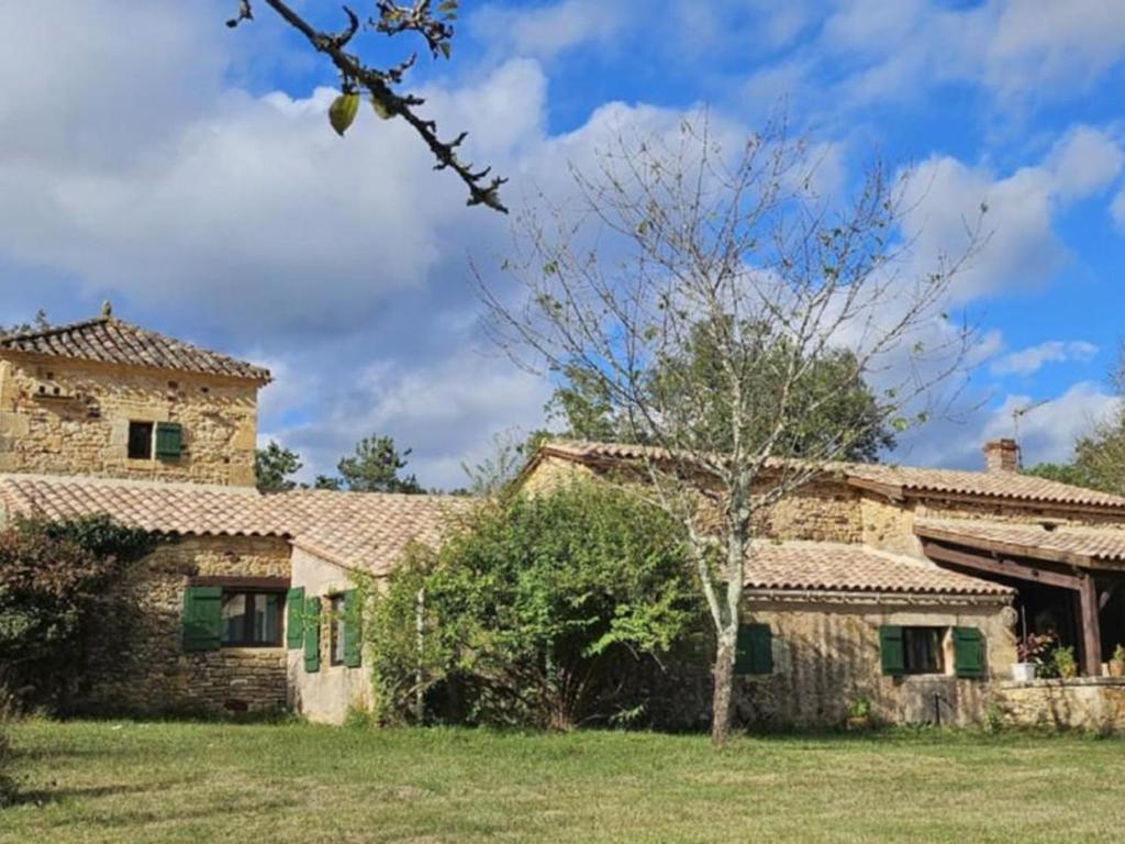 an old stone house with a tree in the yard at Gîte 8 personnes avec cheminée et SPA à Biron - FR-1-616-481 in Biron