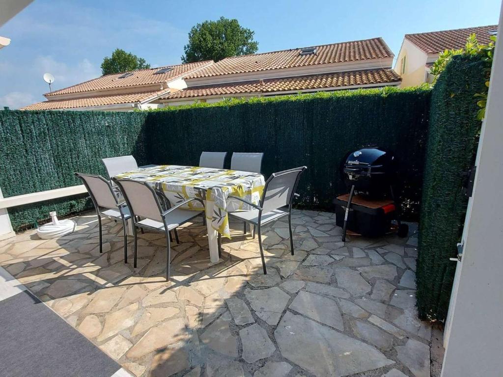 un patio avec une table, des chaises et un barbecue dans l'établissement Maison mitoyenne 3 pièces avec terrasse et parking privé - FR-1-326-855, à Marseillan