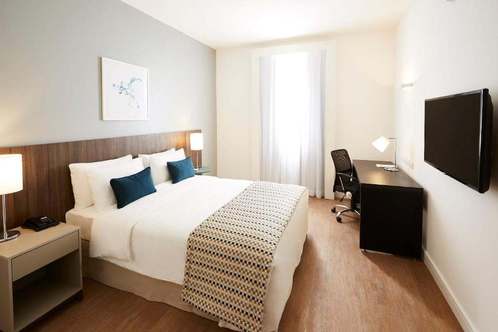 una camera d'albergo con un grande letto e una scrivania di Tulip Inn Itaguai a Itaguaí