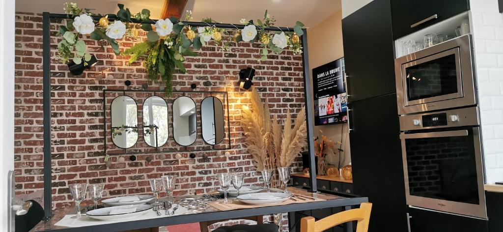une pièce avec un mur de briques et une table avec des miroirs dans l'établissement Maison de village Cosy, à Villelongue-de-la-Salanque