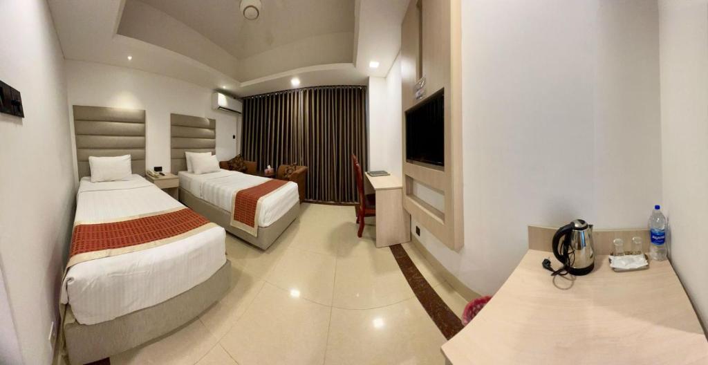 a hotel room with two beds and a television at Marino Hotel - Best near Airport in Dhaka