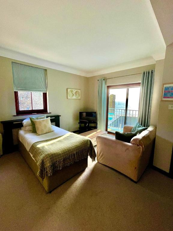 a bedroom with a bed and a couch and a window at No: 1 The Esplanade Guest Accommodation. in Tenby