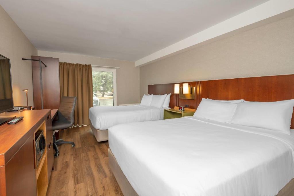 a hotel room with two beds and a desk at Comfort Inn in Ottawa