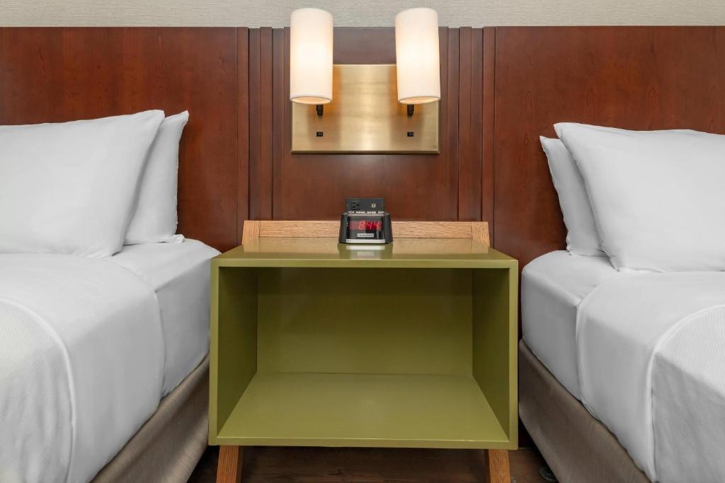 a table with a clock on it next to two beds at Comfort Inn in Ottawa