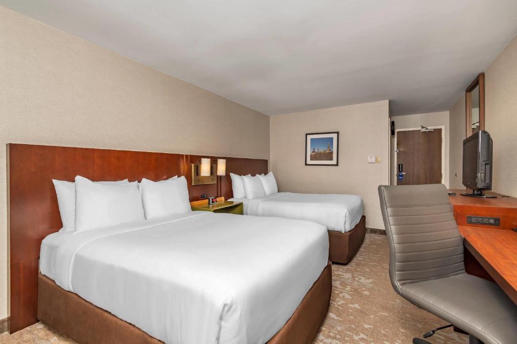 a hotel room with two beds and a desk at Comfort Inn in Ottawa