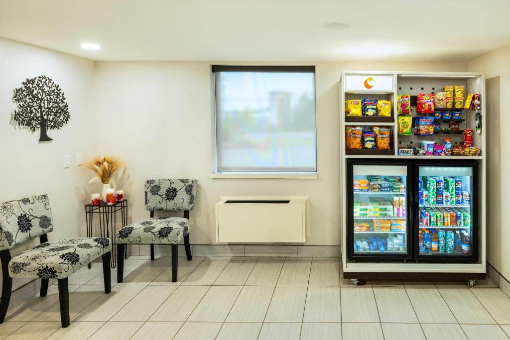 a room with a refrigerator and two chairs and a window at Comfort Inn in Charlottetown