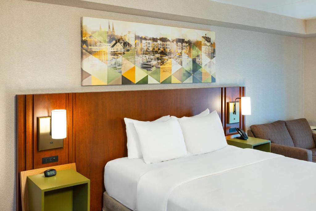 a bedroom with a white bed and a couch and a chair at Comfort Inn in Charlottetown
