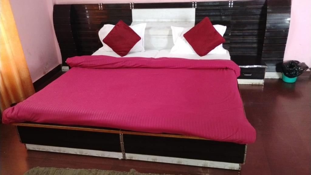 a bed with red and white pillows on it at Hotel bhagirathi darshan in Jāmb