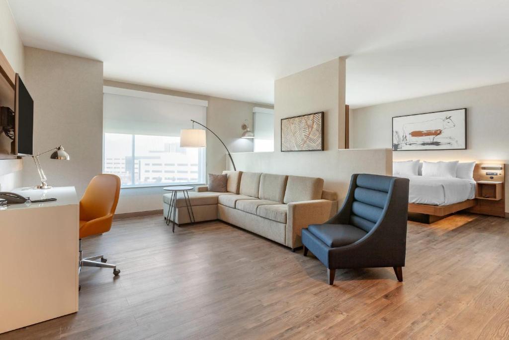 a hotel room with a bed and a couch and chair at Cambria Hotel Plano - Richardson Garland in Richardson
