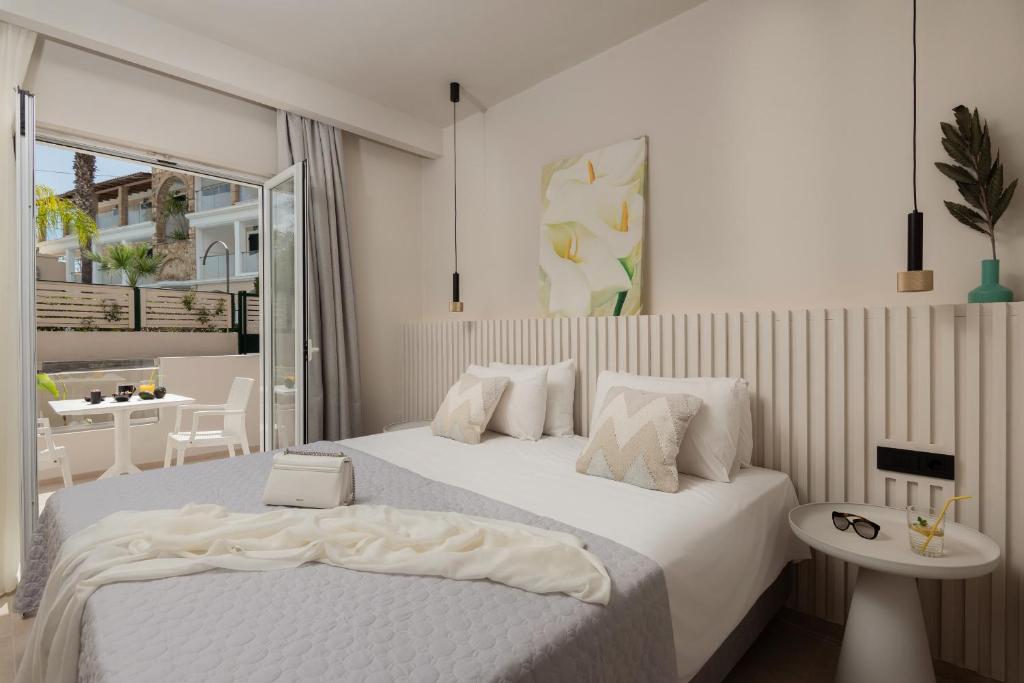 a white bedroom with a bed and a table at Nikos & Maria Studios II in Laganas