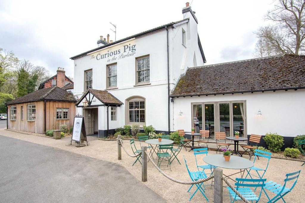 un edificio con mesas y sillas delante de él en The Curious Pig in the Parlour, en Burstow