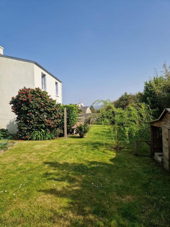 une cour herbeuse avec une maison et un bâtiment dans l'établissement Maison quartier calme, à 600m de la plage, jardin clos exposé sud, à Le Relecq-Kerhuon