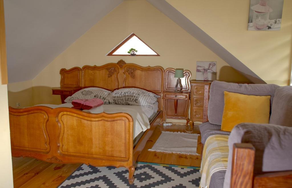 1 dormitorio con cama grande de madera y sofá en Młyńskie Schody, en Staroscin