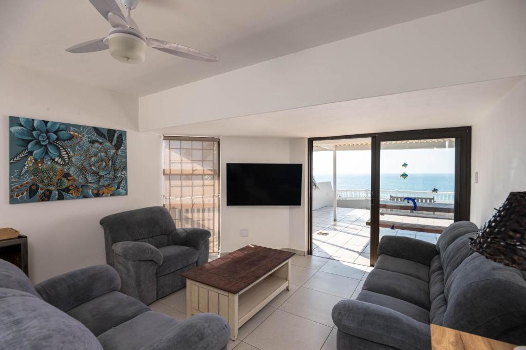 a living room with a couch and chairs and a tv at Le Roc 10 in Ballito