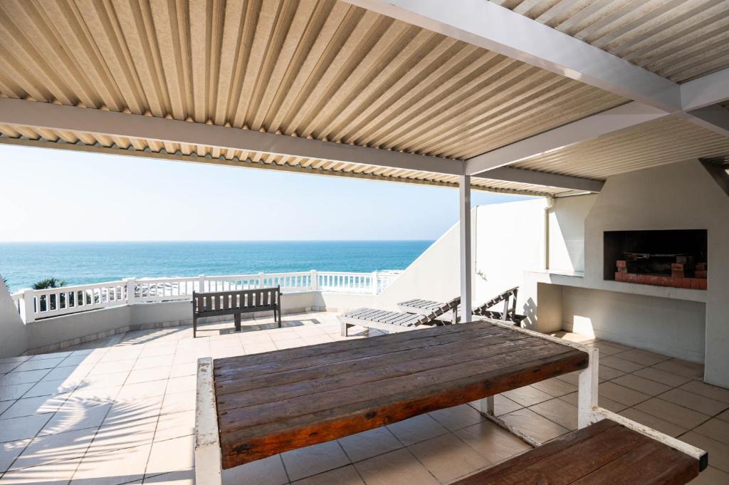 a patio with a wooden bench and the ocean at Le Roc 10 in Ballito