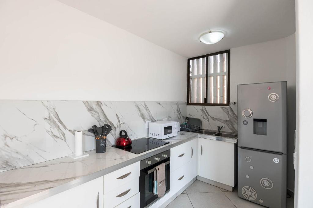 a kitchen with white counters and a stainless steel refrigerator at Le Roc 10 in Ballito