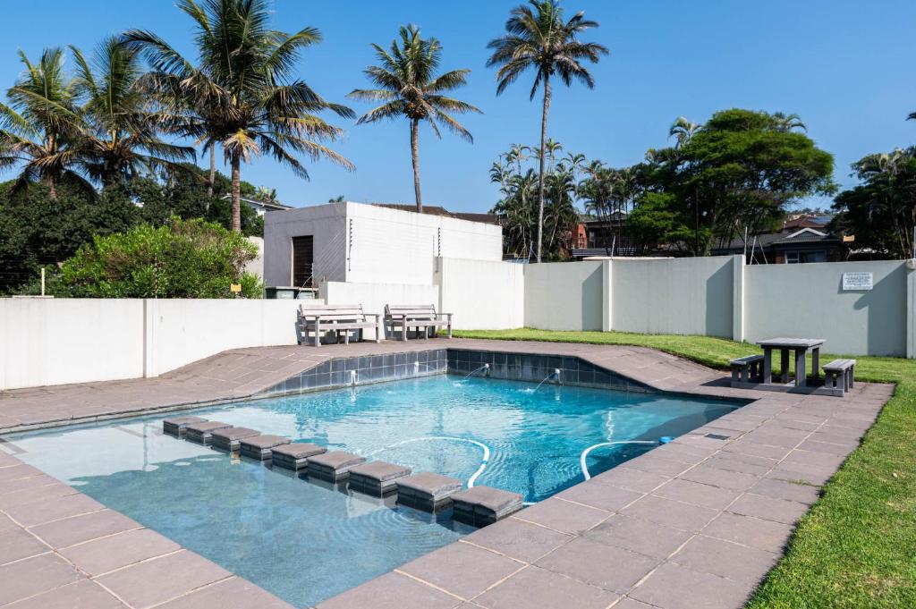 a swimming pool with a table and chairs in a yard at Le Roc 10 in Ballito