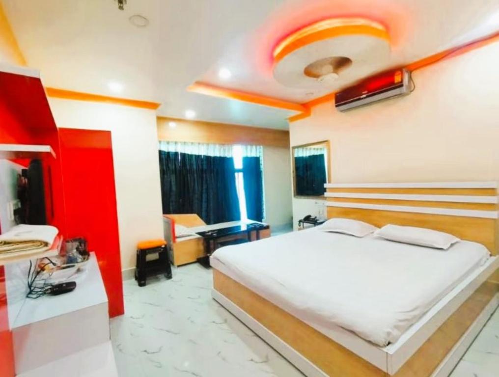 a bedroom with a white bed and a red wall at Hotel Anurag Palace In Agartala in Agartala