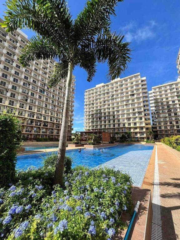 a palm tree and two buildings with a swimming pool at Saekyung Condo in Lapu Lapu City