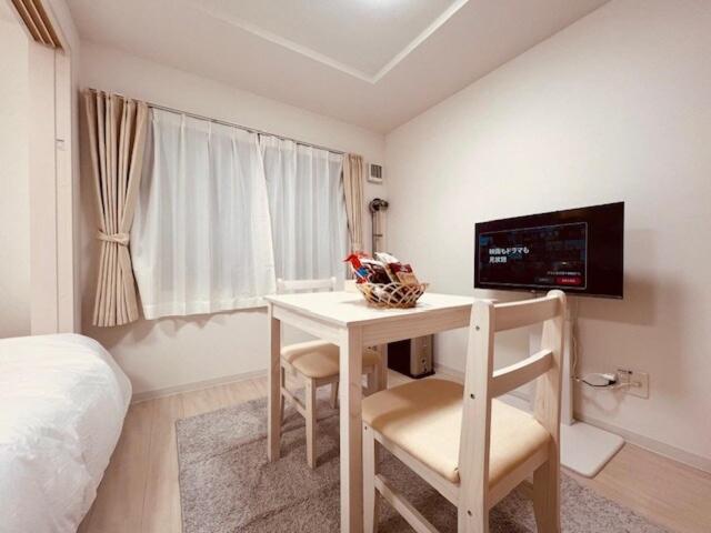 1 dormitorio con escritorio, TV y cama en Raffine103, en Sapporo