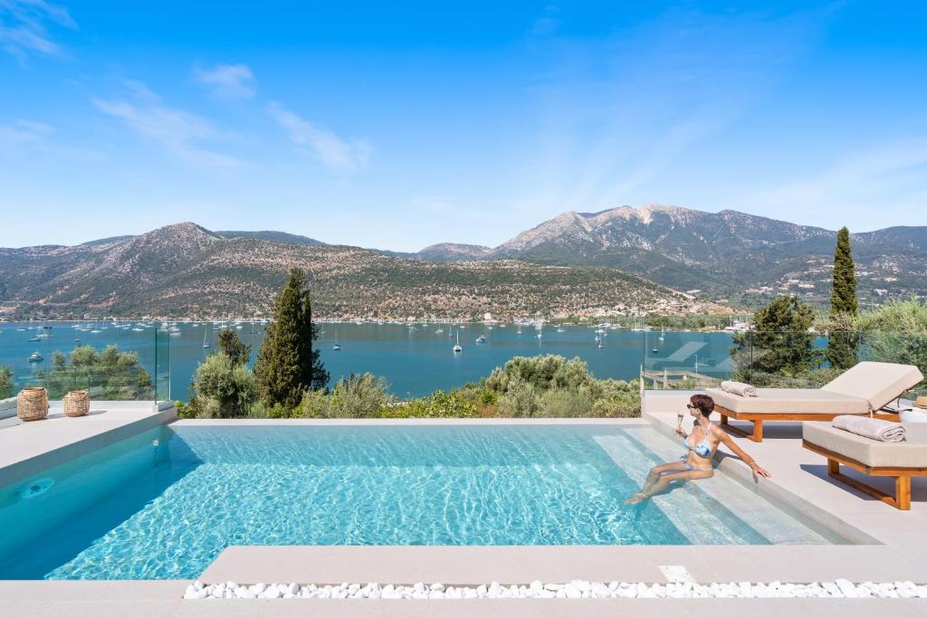 a woman sitting in a swimming pool with a view of the water at Villa Olea in Yenion