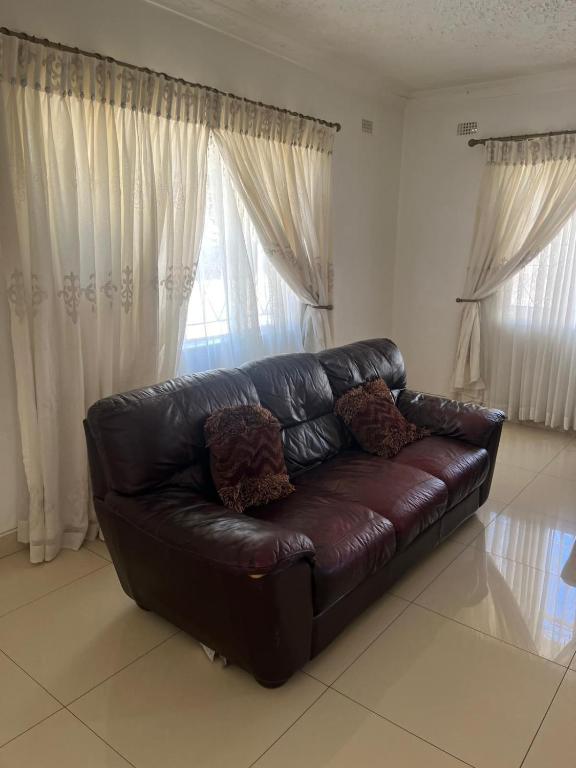 a brown leather couch sitting in a living room at Wales Suite in Harare