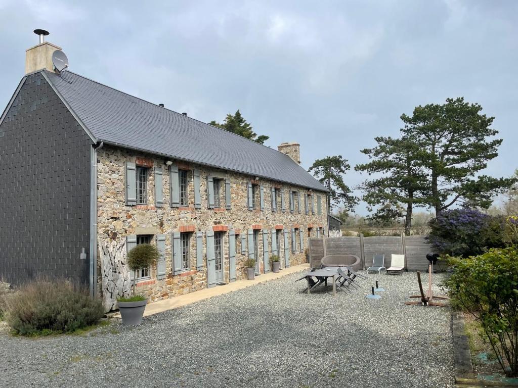 a brick building with a table and chairs in a courtyard at Gite Ouest de la pointe d'Agon in Agon Coutainville