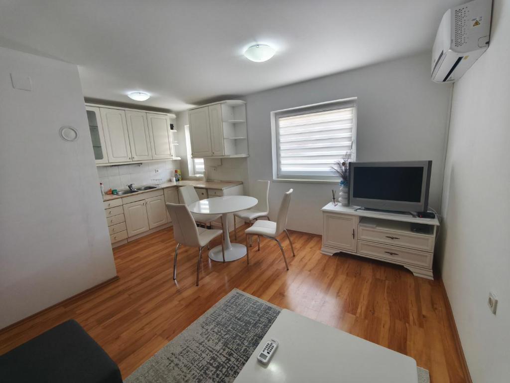 a living room with a table and a tv and a kitchen at Depandans Stefan in Nevesinje