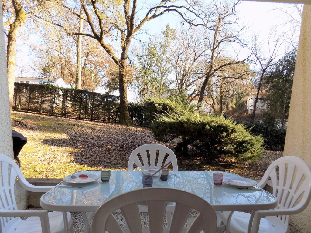 une table avec des chaises blanches et une table avec des chaises bleues dans l'établissement Saint Georges de Didonne - STUDIO CABINE - résidence boisée proche PLAGE, à Saint-Georges-de-Didonne