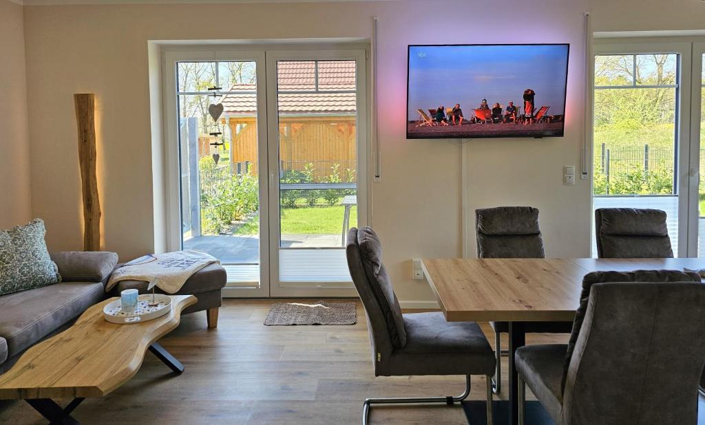 ein Wohnzimmer mit einem Tisch und einem Fernseher an der Wand in der Unterkunft Ferienhaus Liv in Biendorf